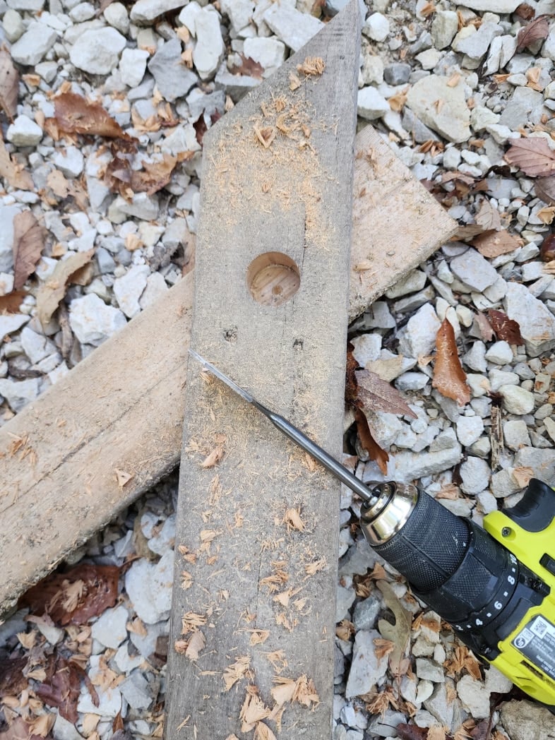 deck board with a hole and a paddle bit on a drill