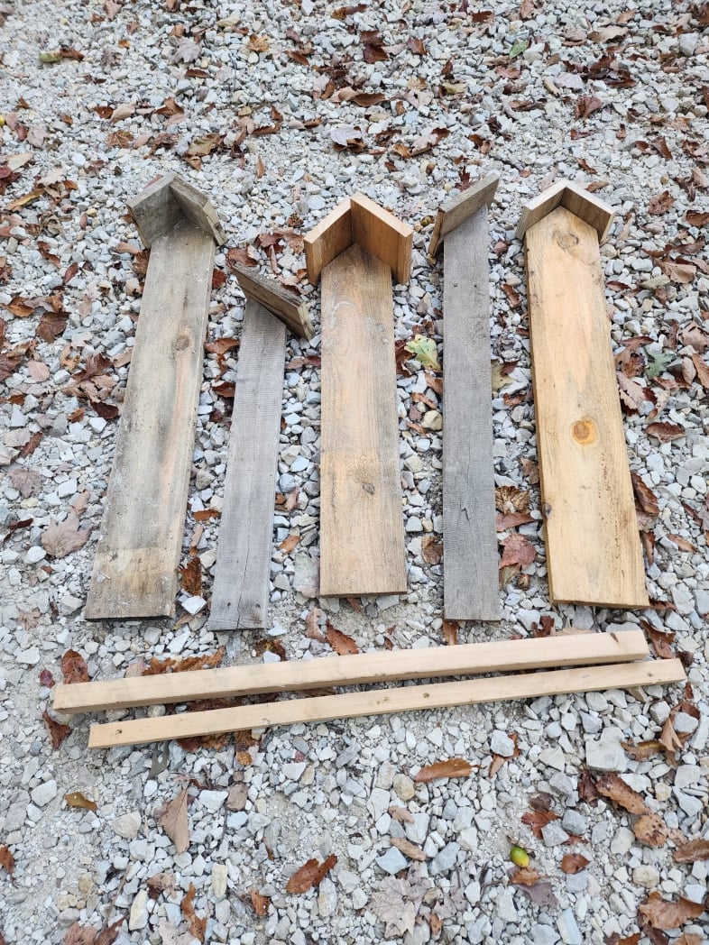 weatherd boards laying on gravel driveway look like tall birdhouses