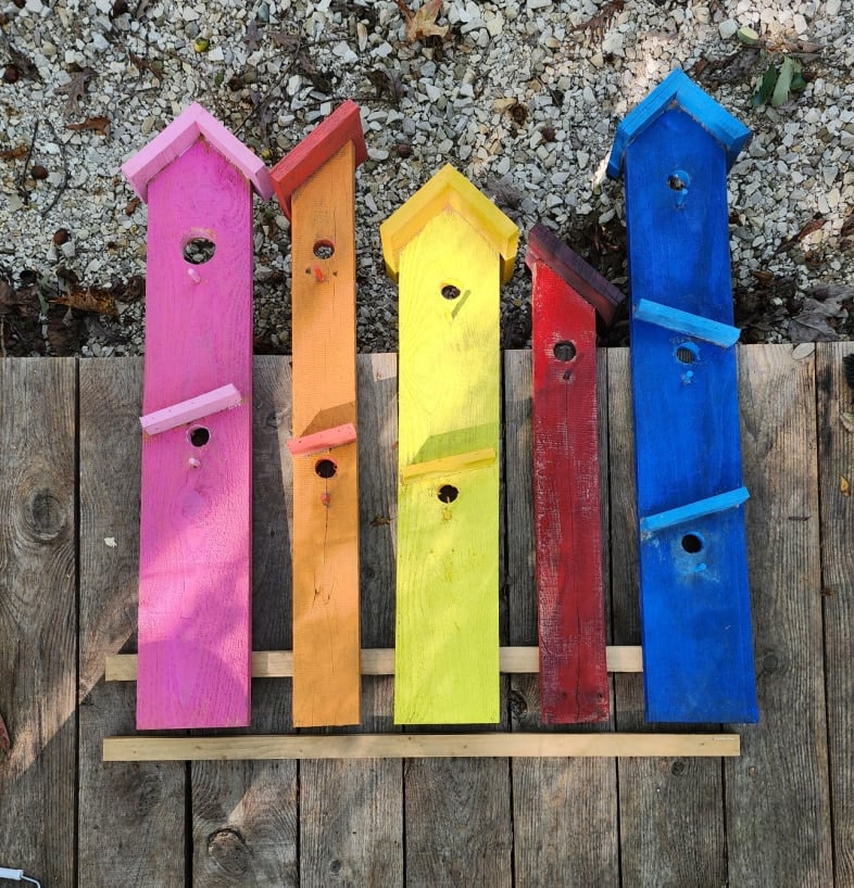 painted birdhouse boards laying cloe together on a deck