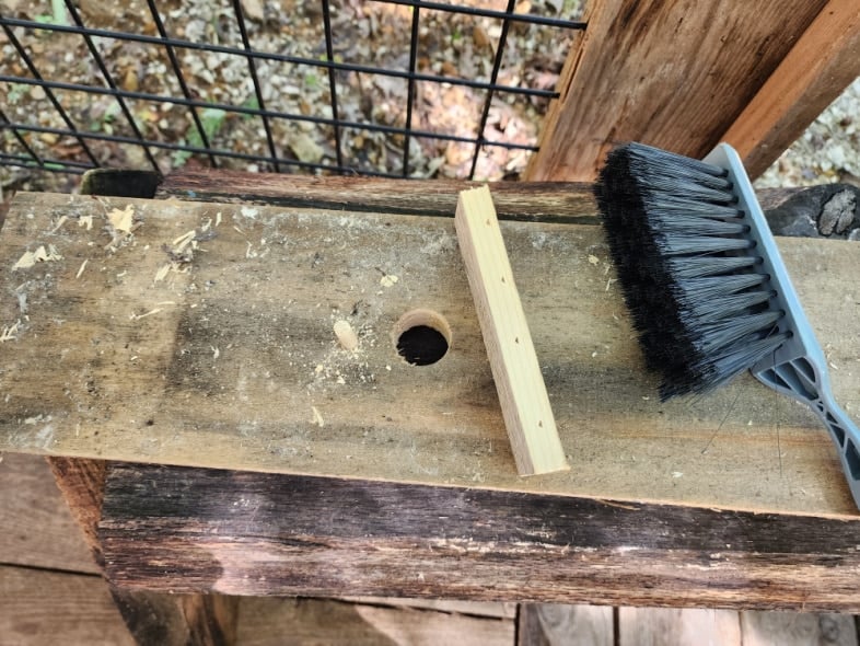 hand dust brush laying on faux birdhouse board