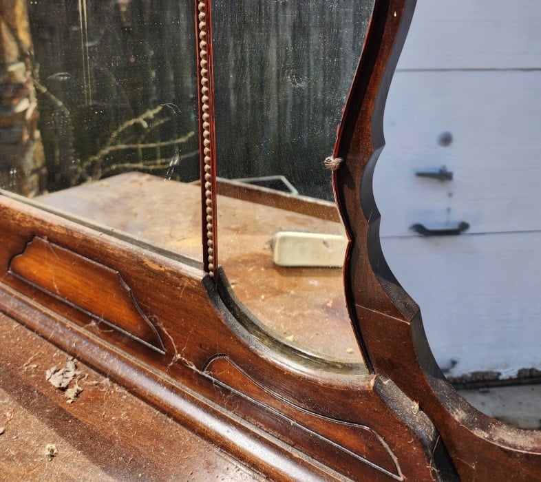 closeup of mirror attached to antique dresser