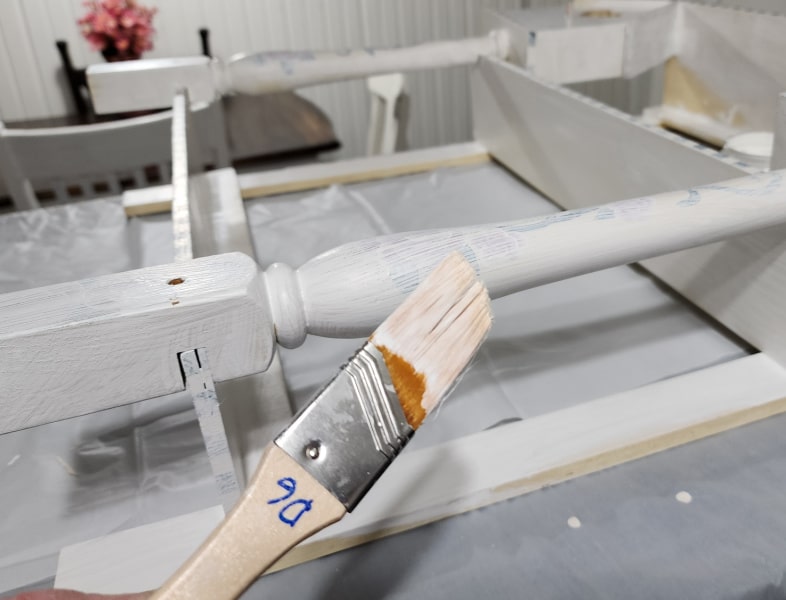 small paint brush painting a shelf spindle white