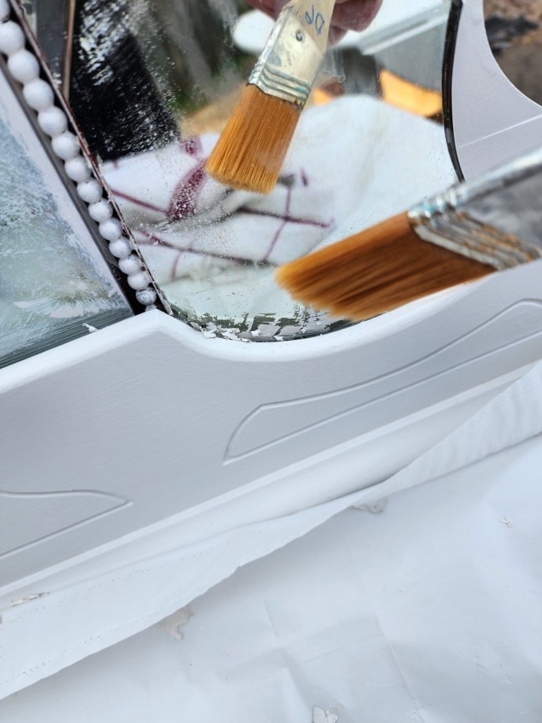 small paint brush removing paint chips and crumbs from mirror frame