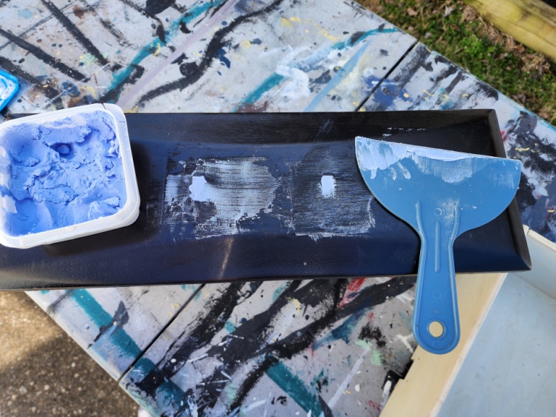 blue drywall patch and putty knife fill hardware holes