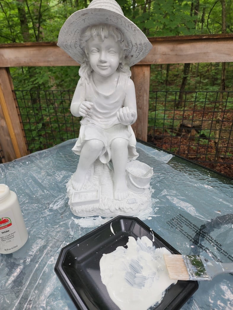 painting a basecoat of white on a plaster little girl garden statue