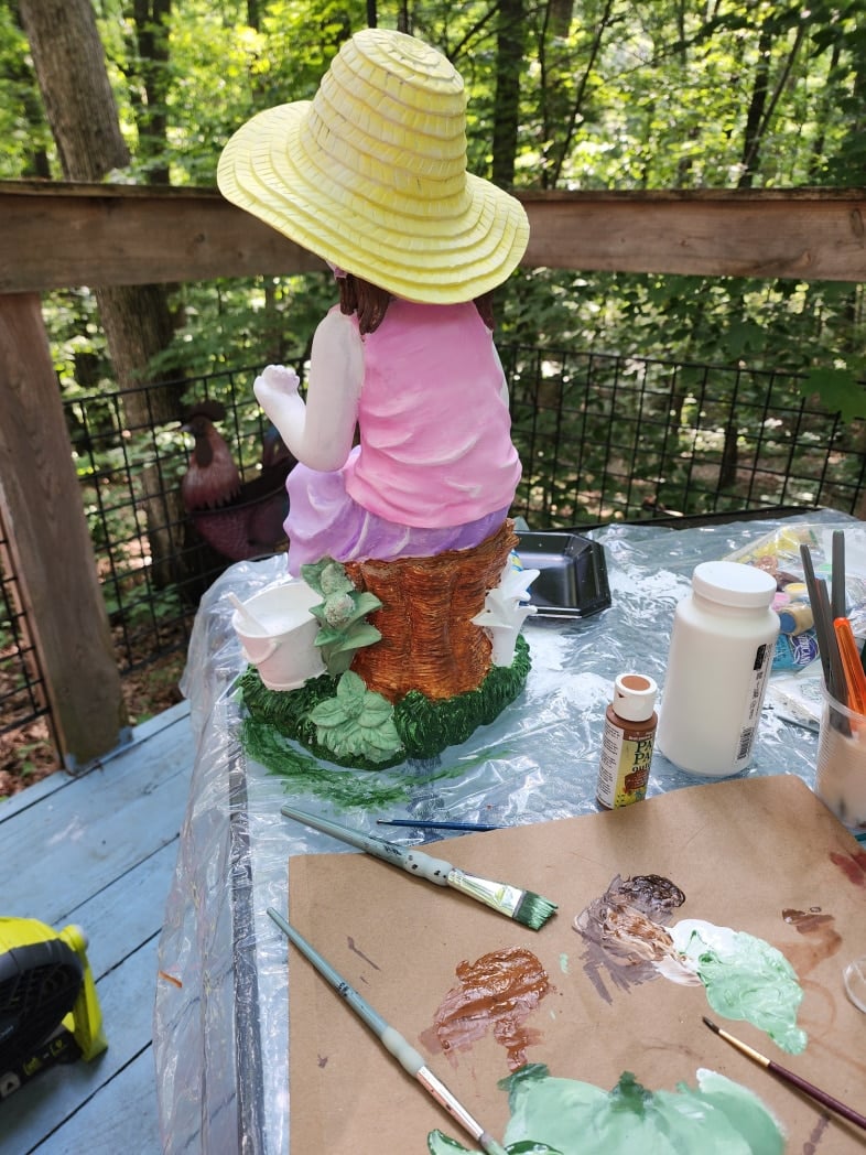painting shades of green on the little girl statue grass and leaves