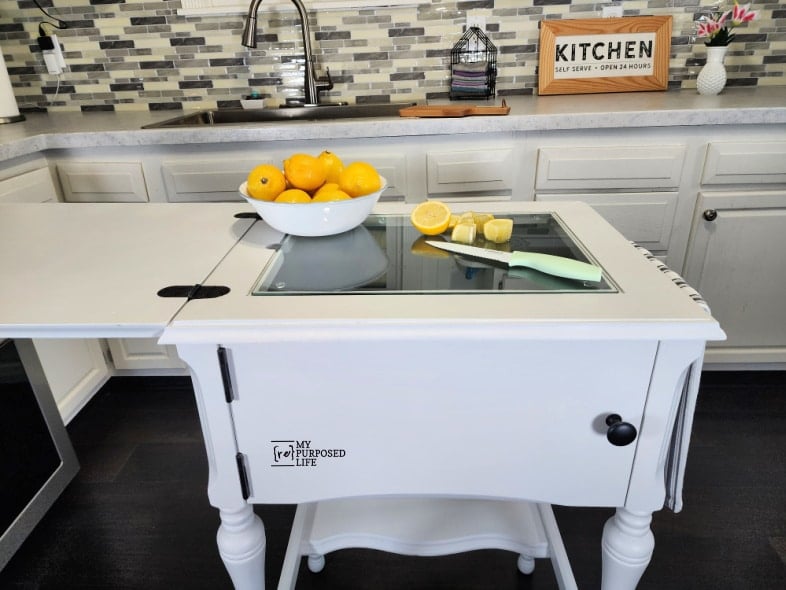 front view of small kitchen island with a glass cutting board insert