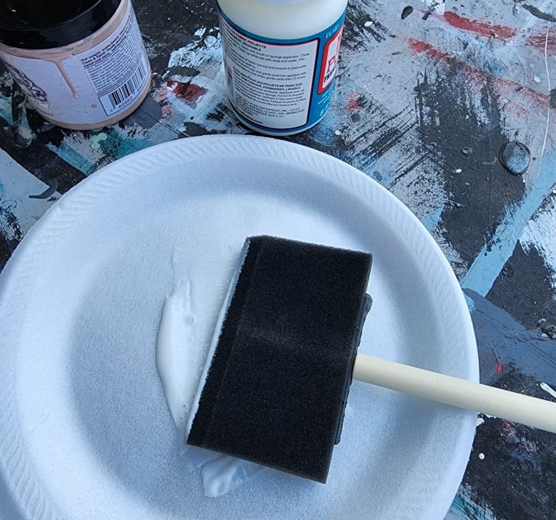 mod podge on a styrofoam plate with a large foam brush