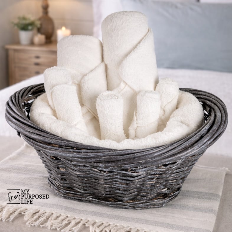 dark basket whitewashed holding rolled towels