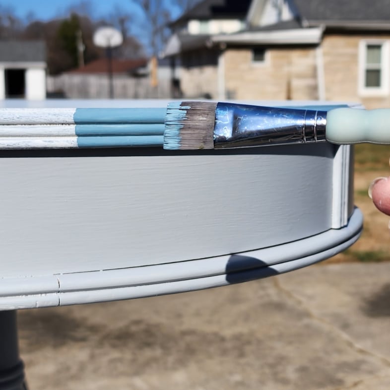 small trim brush paints edge of a drum table