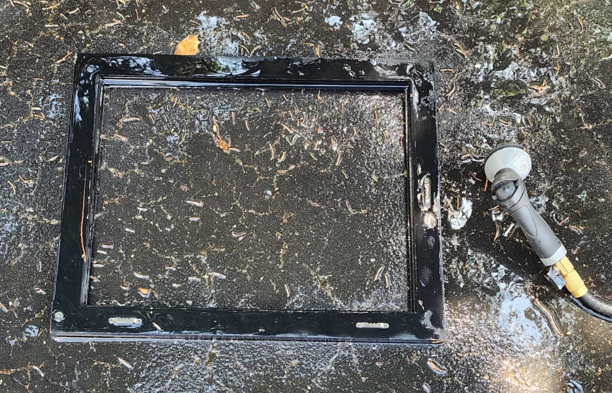 spraying a thrift store frame with a garden hose