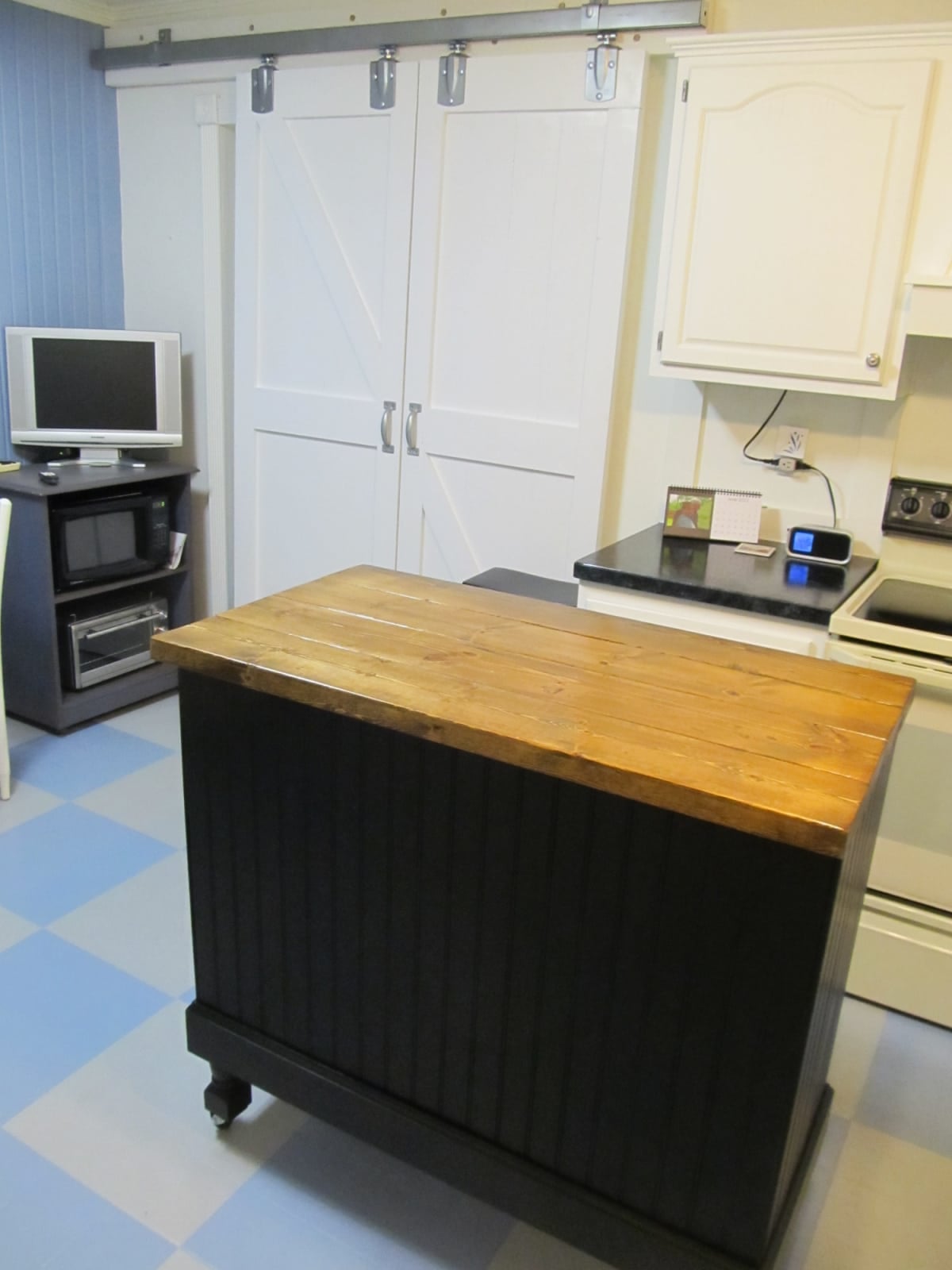 black kitchen island with a warm stained top in a kitchen with barn doors