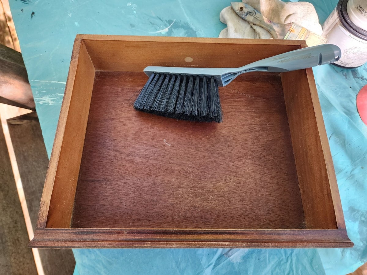 using a hand dust brush to clean thrift store furniture