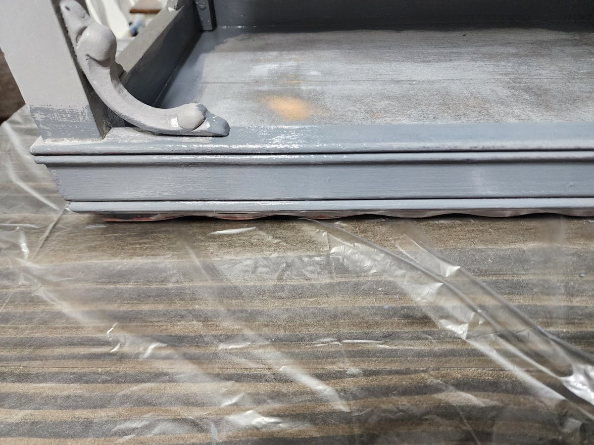 painting a side table upside down with a small paint brush